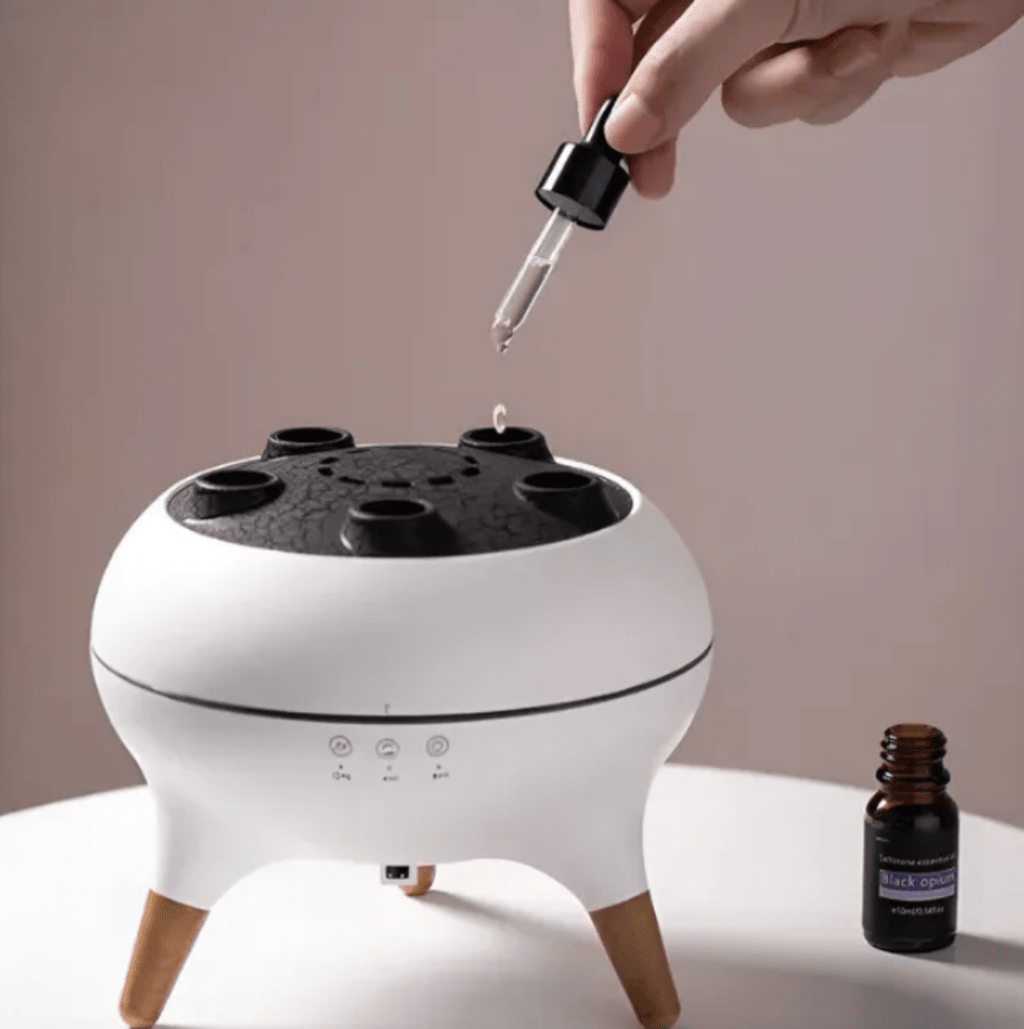 White diffuser with black top being used to add essential oil droplets.